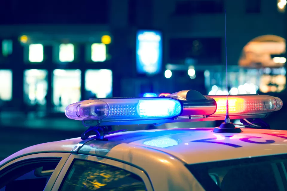 Nighttime view of blue and red lights on top of a white police car.